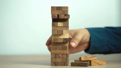Business risks concept. Hand pulls out wooden brick with jenga game. jenga fa Stock Footage 129961578