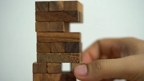 Business risks concept. Hand pulls out wooden brick with jenga game. jenga fa Stock Footage 129961589