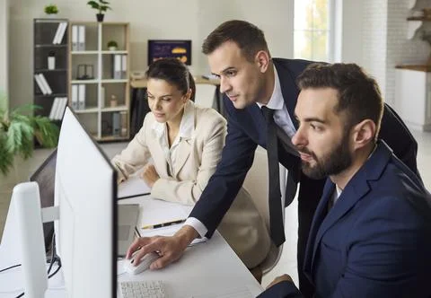 Business team analyzing data on computer in office, planning strategy together Stock Photos