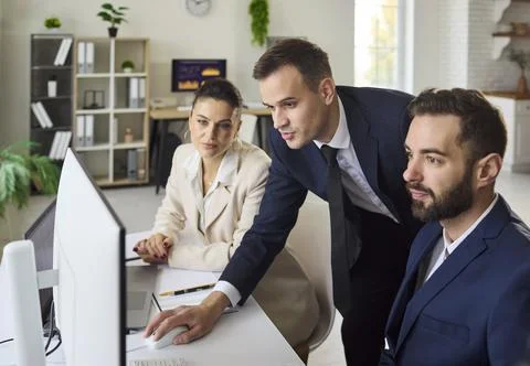 Business team analyzing data on computer in office, planning strategy together Stock Photos