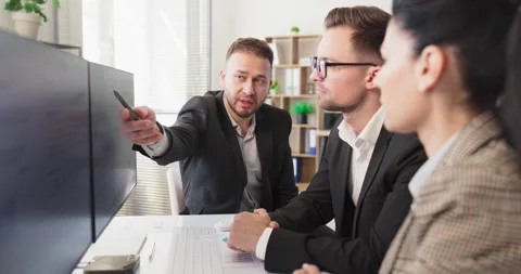 Business team analyzing data on monitors during strategy discussion in office Stock Footage 340539470