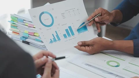 Business team analyzing data using charts and graphs on paperwork Stock Footage 325446773