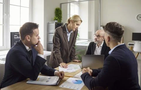 Business team brainstorming strategy at table with charts, laptop, papers in Stock Photos
