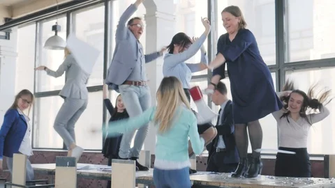 A business team cheerfully dances on a table in an office space, sings into a Stock Footage 111655941