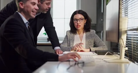 Business team collaborating and analyzing data at desktop computer in modern Stock Footage 333870439
