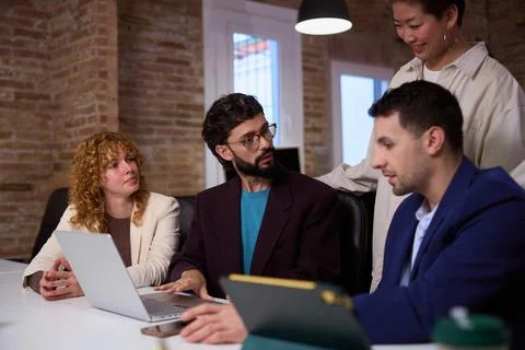 Business team collaborating on project using laptop and tablet in office meeting Stock Photos