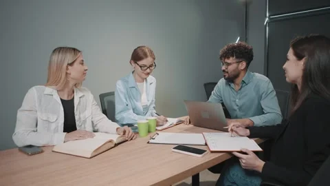 Business team discusses documents in a modern office setting during a meeting Stock Footage 318523571