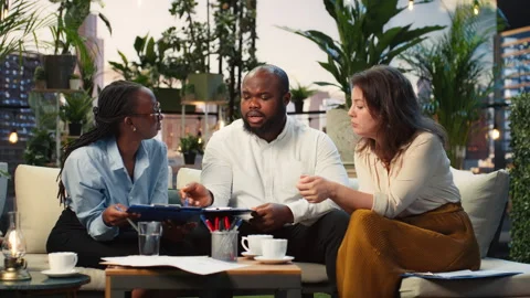 Business team discusses project documents during rooftop meeting Stock Footage 345166335