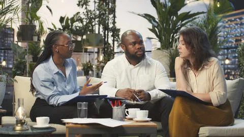 Business team discusses project documents during rooftop meeting Stock Photos