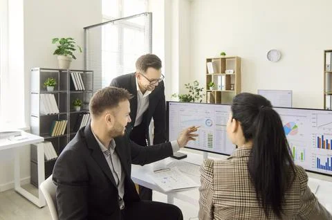 Business team discussing analytics on computer screens in office strategy Stock Photos