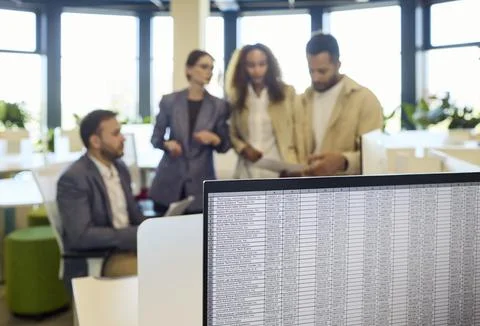 Business team discussing data strategy near computer with spreadsheet on screen Stock Photos
