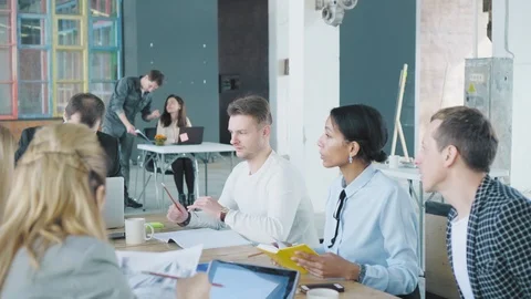 A business team is discussing a project at a large office table. Creative office Stock Footage 108182595