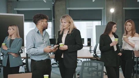Business team engages in a discussion while holding cups in office setting 스톡 동영상 312259343