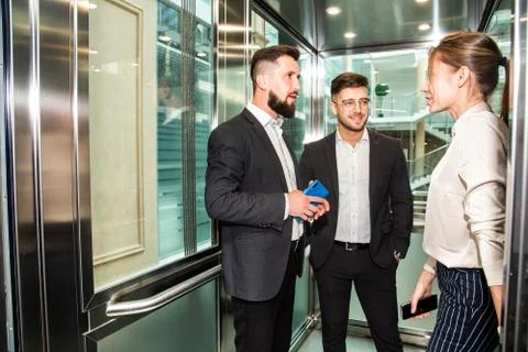 Business team group going on elevator. Business people in a large glass elevator Stock Photos