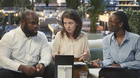 Business team looking at tablet display, comparing information on rooftop lounge Stock Photos