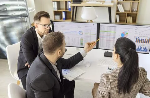 Business Team Reviewing Data Analytics on Dual Screens Office Strategy Meeting Stock Photos