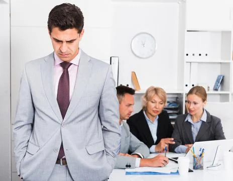 Business team solving problems with upset man foreground Stock Photos