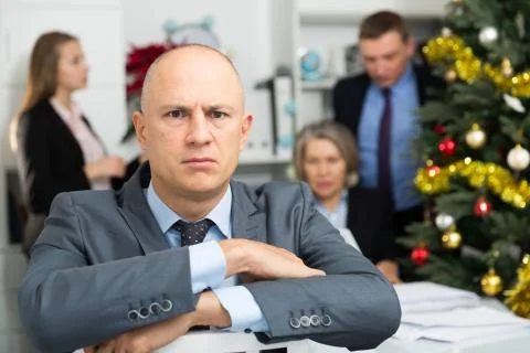 Business team tensely solving problems in office with offended man foreground 库存照片