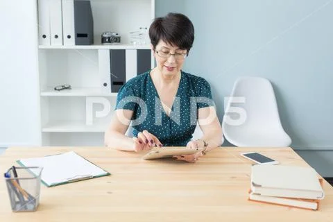 Business, technology and people concept - middle aged woman using a gadget in Stock Photos