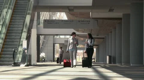 Business travelers walking through airport with bags Stock Footage
