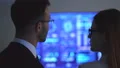 The business woman and a man talking near the blue display 4k or 4k+ Resolution
