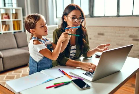 Business woman and mom are trying to work on a laptop when her little daughte Stock Photos