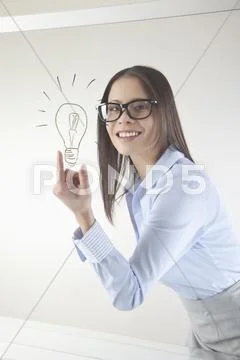 Business woman with drawn light bulb on wipe board, smiling, portrait Stock Photos