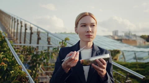 Business woman eats vegetables using chopsticks standing on office building roof Stock Footage 215176986