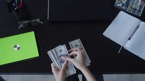 Business woman hand counts stack of dollars on table on which there is digital Stock Footage 159075285
