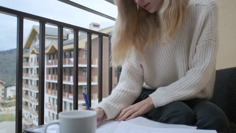 Business woman making notes in documents while sitting on the balcony Stock Footage 145643559