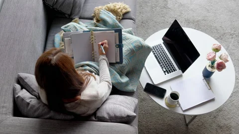 Business woman taking notes while comfortably sitting on her couch at home. Stock Footage 130597974