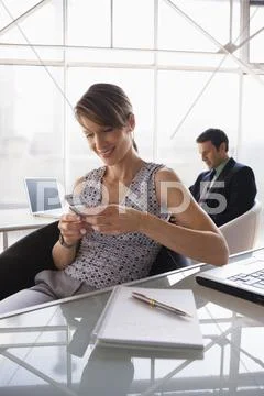 Business woman using a mobile phone, male colleague in background Stock Photos