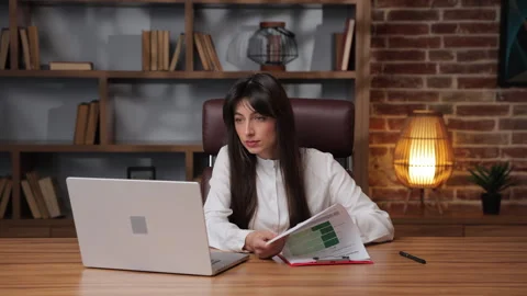 Business woman working on documents while looking at laptop. Stock Footage 331778006