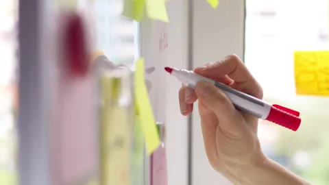 Business woman's hand writes a note with a marker on a white board  Stock Footage 156861280