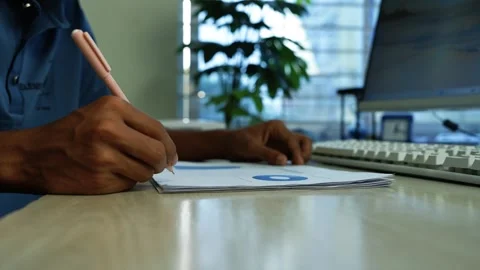 Business worker writing notes at office desk, Close-up of a business worker.. 動画素材 346484093