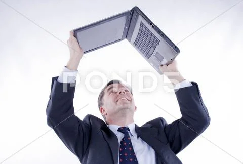 Businessman, 50+, holding a laptop above his head Stock Photos