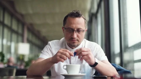 Businessman adding sugar to coffee while working in cafe. Stock Footage 156191833