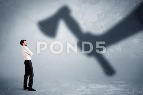 Businessman afraid of a huge shadow hand holding an axe concept Stock Photos