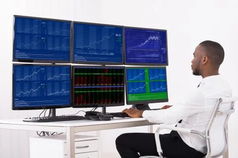 Businessman Analyzing Data Displayed On Multiple Computer Screens In Office Stock Photos