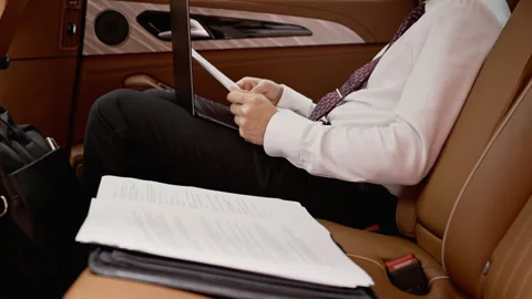 Businessman Analyzing Documents and Working on Laptop in Luxury Car Stock Footage 339676525