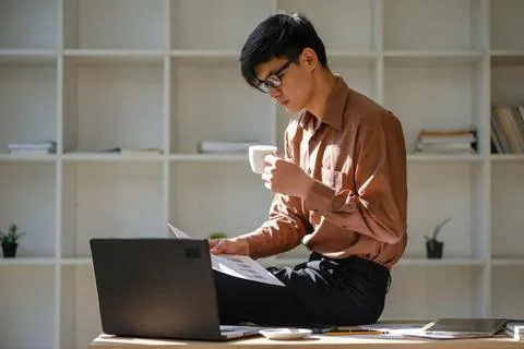 Businessman analyzing financial reports while drinking coffee in a modern o.. Stock Photos