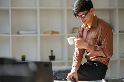 Businessman analyzing financial reports while drinking coffee in a modern o.. Stock Photos