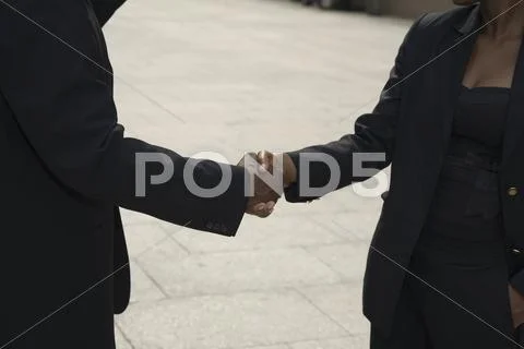 Businessman and businesswoman shaking hands outside, midsection Stock Photos