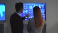 The businessman and a businesswoman talking near the blue display 4k or 4k+ Resolution