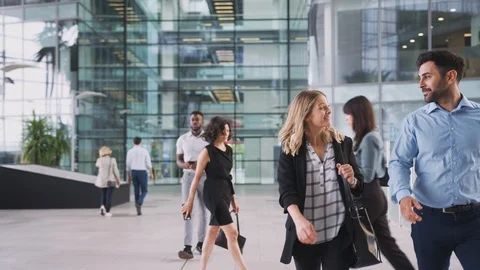 Businessman And Businesswoman Walking Through Lobby Of Busy Modern Office Stock Footage