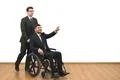 The businessman and a disabled gesturing on the white wall background Photo