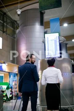 Businessman and woman looking at departure board Stock Photos