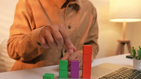 A businessman arranges colored blocks into stacked layers. Stock Footage 317599605