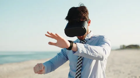 Businessman with augmented reality viewer in metaverse beach Stock Footage 195989202