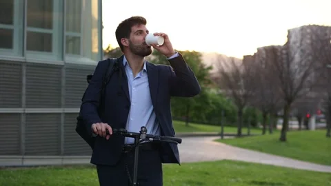 Businessman with backpack drinking coffee next to electric scooter at dawn .. Stock Footage 276509878